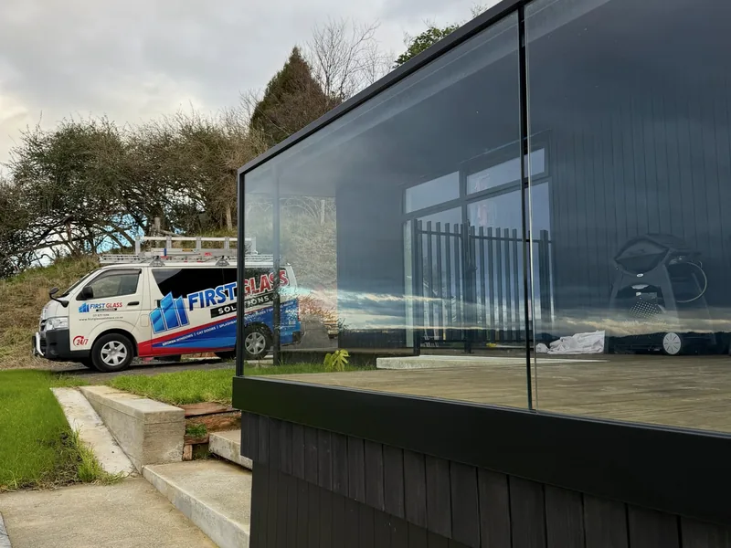 Glass balustrade panel fitted to the deck of a dark clad home