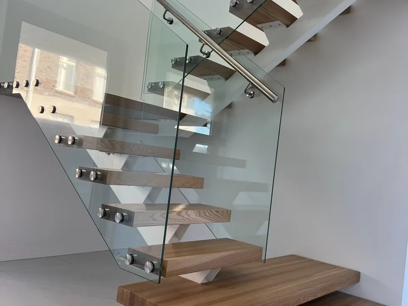 Frameless glass stair balustrade with standoff fixings and a timber handrail