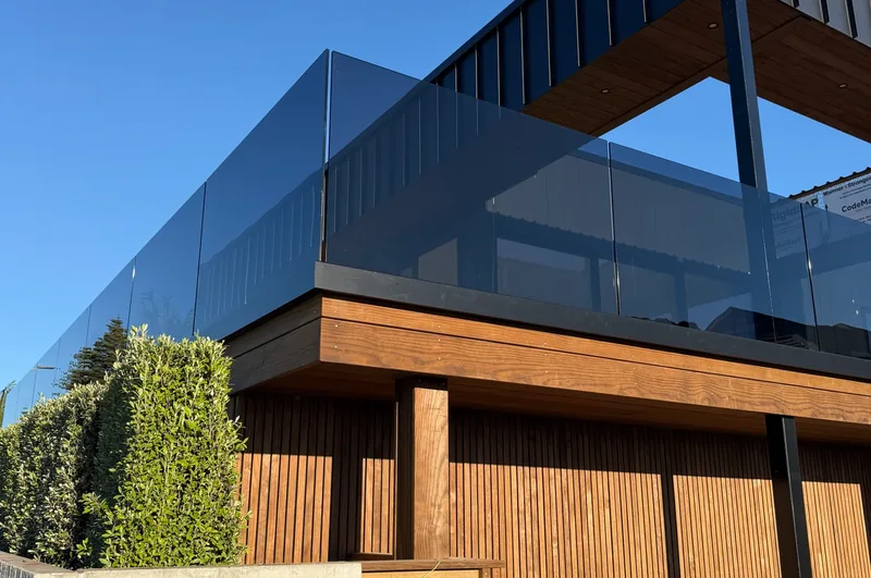 Glass balustrade on the upper deck of a timber-clad home from the First Glass gallery