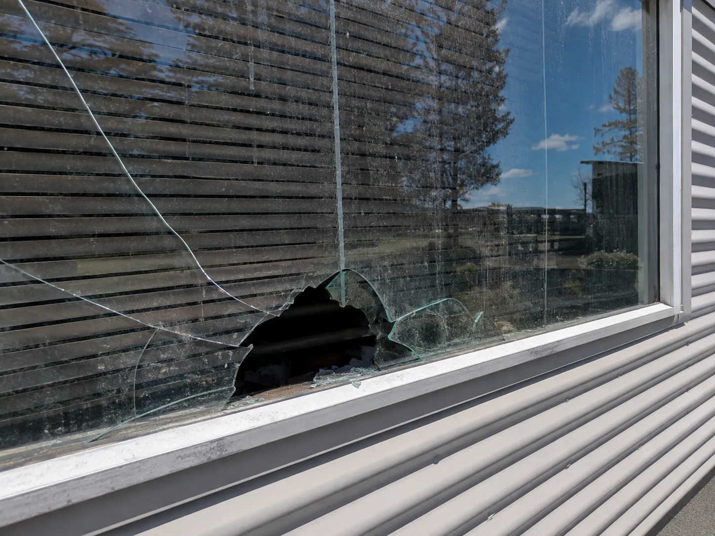 Glazier boarding up a broken window at night