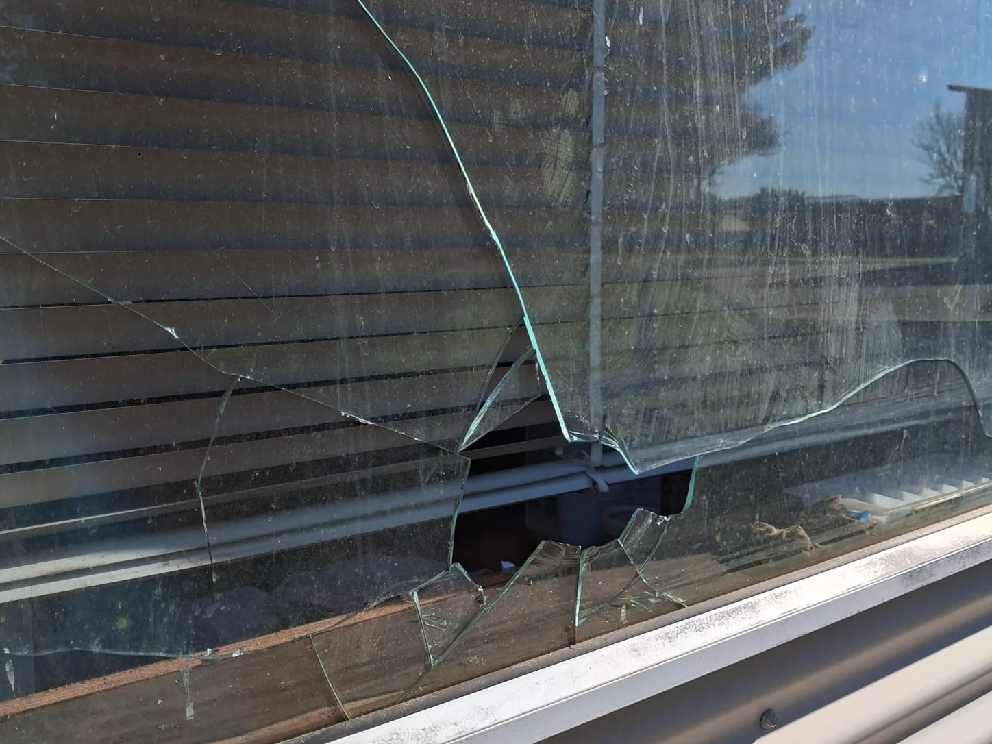 A window pane smashed right through, glass still in the frame