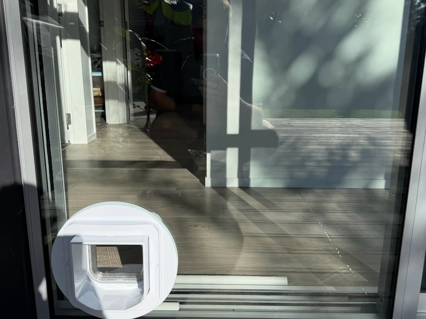 A white flap pet door fitted into a sliding glass door