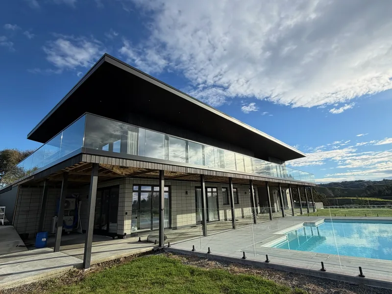Frameless glass pool fence in front of a modern home