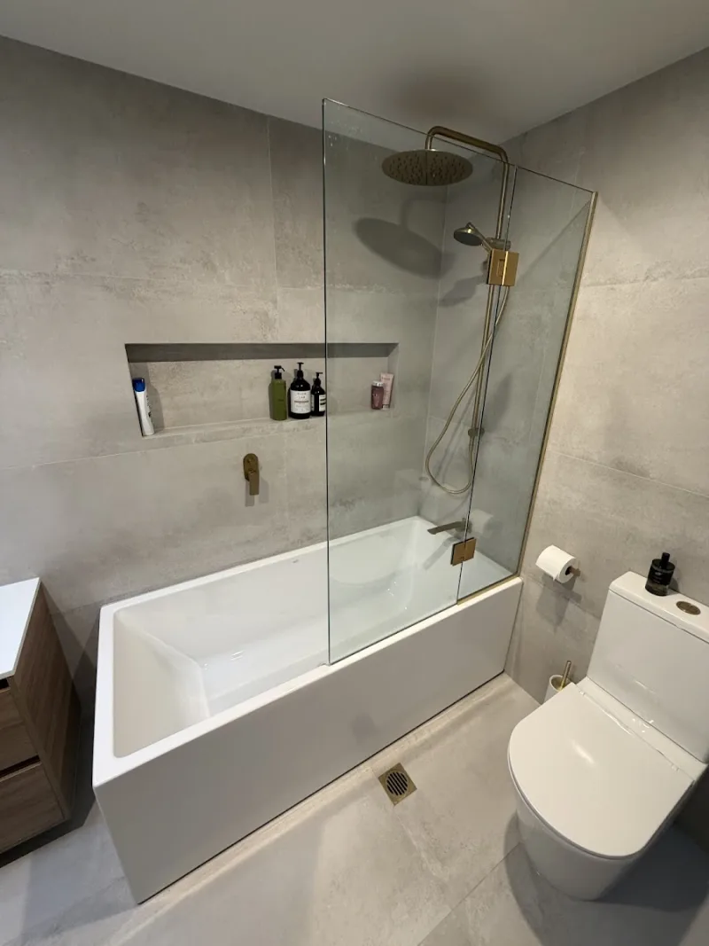 Frameless glass bath screen with brass shower fittings in Tauranga