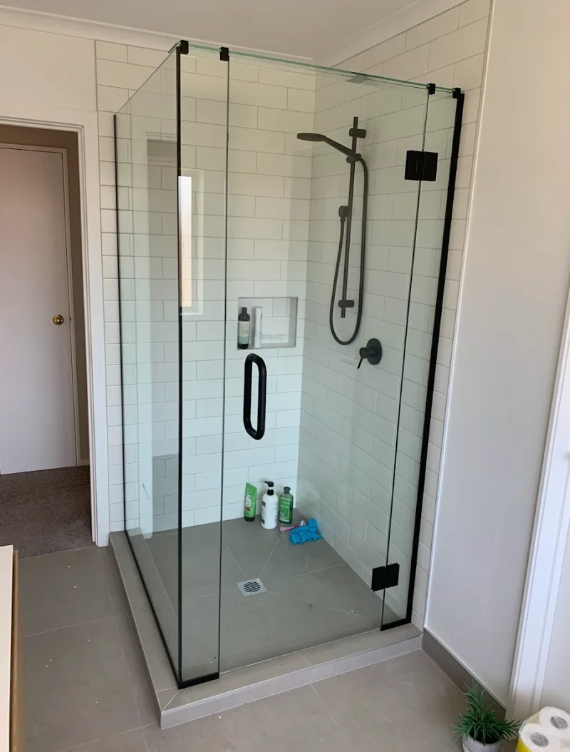 Frameless corner shower with black hardware on white subway tiles in Tauranga