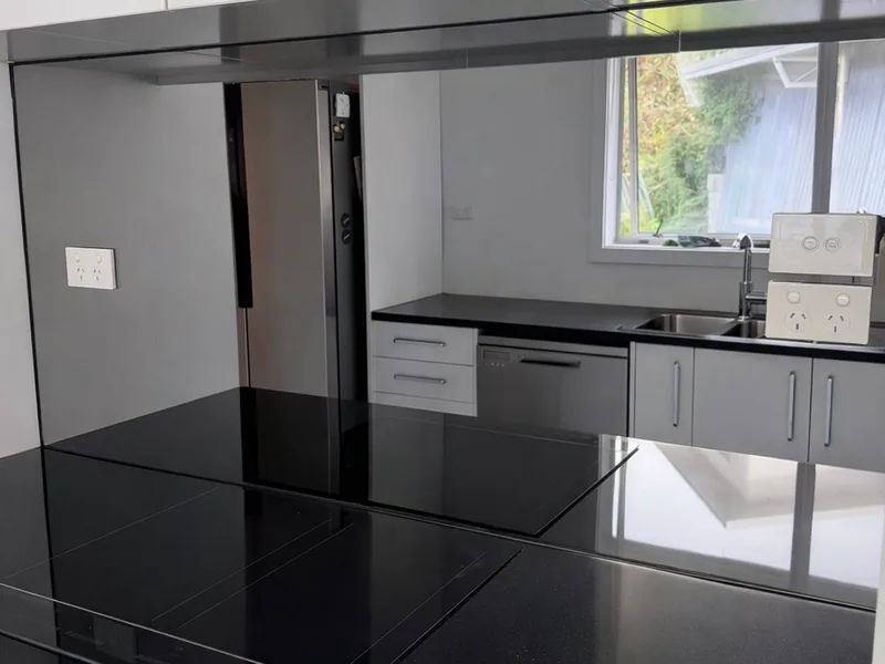 Black gloss glass splashback running the length of a kitchen bench