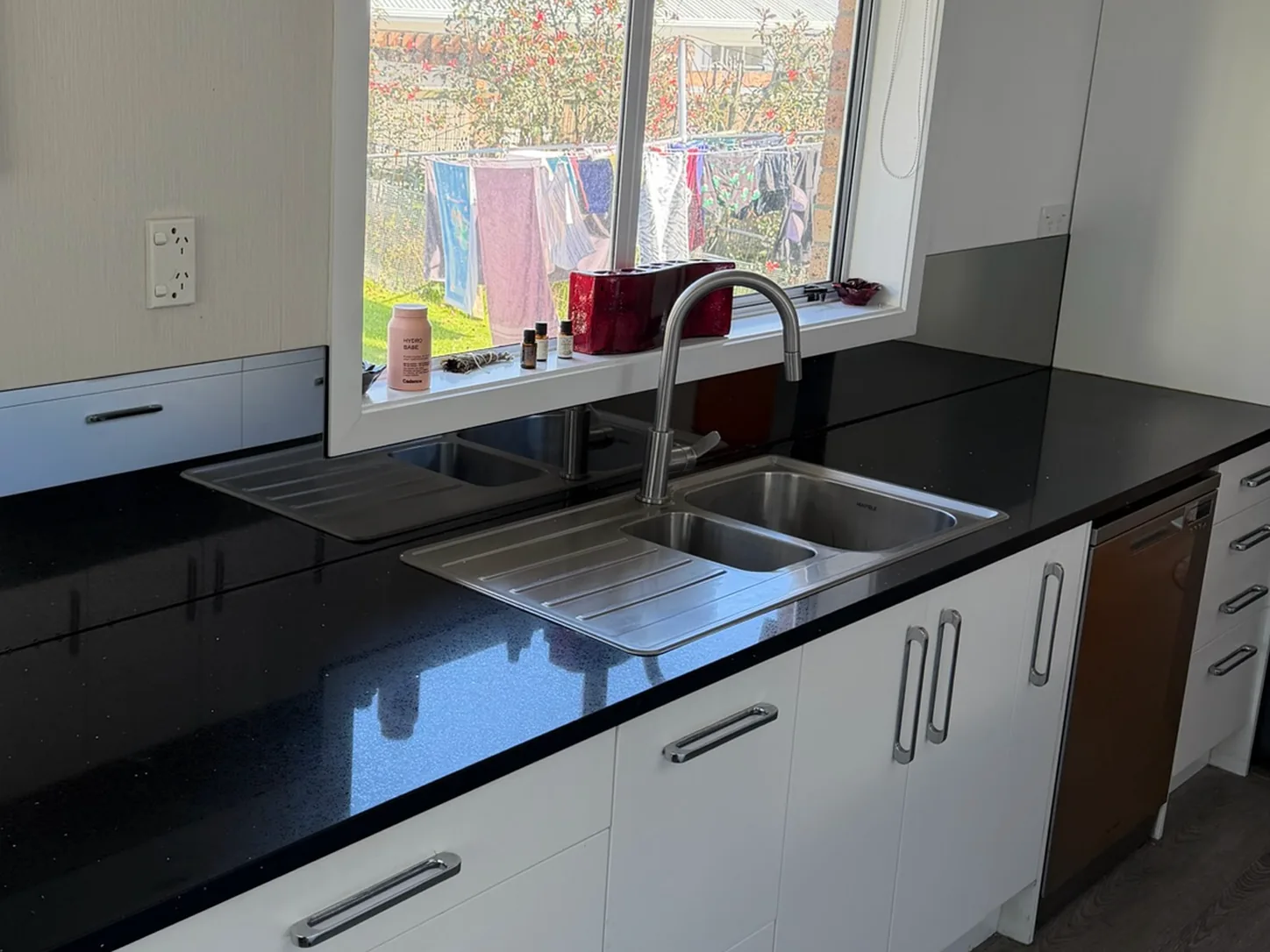Black glass splashback behind the sink in a Tauranga kitchen
