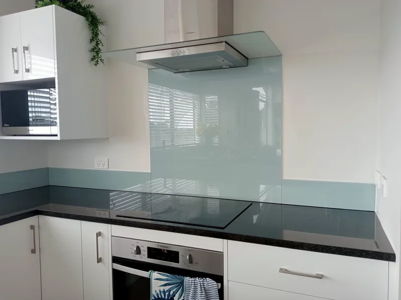 Pale blue green glass splashback behind a cooktop in a Tauranga kitchen